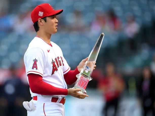 Shohei Ohtani of the Los Angeles Angels holds his American League Player of the Month award presented to him before the game against the Seattle...