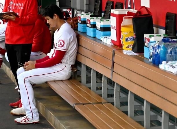 Shohei Ohtani of the Los Angeles Angels looks at an iPad in the dugout before the game against the Seattle Mariners at Angel Stadium of Anaheim on...