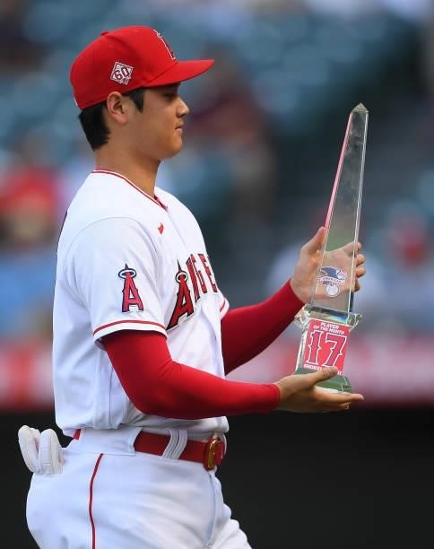 Shohei Ohtani of the Los Angeles Angels holds his American League Player of the Month award presented to him before the game against the Seattle...