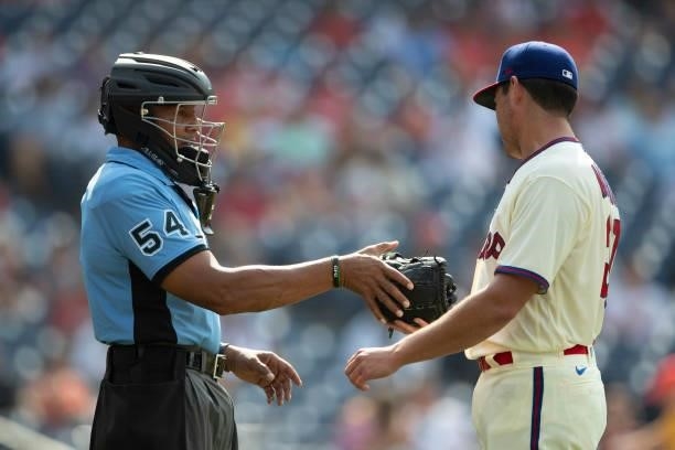 Umpire CB Bucknor asks for the glove of Matt Moore of the Philadelphia Phillies against the Miami Marlins during Game One of the doubleheader at...