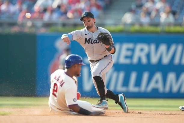 Miguel Rojas of the Miami Marlins attempts to turn a double play against Jean Segura of the Philadelphia Phillies during Game One of the doubleheader...