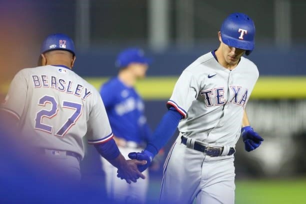 Eli White of the Texas Rangers high-fives Tony Beasley of the Texas Rangers as he rounds the bases after hitting a two-run home run during the ninth...