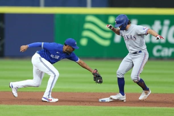 Charlie Culberson of the Texas Rangers beats the tag by Marcus Semien of the Toronto Blue Jays for a double during the third inning at Sahlen Field...