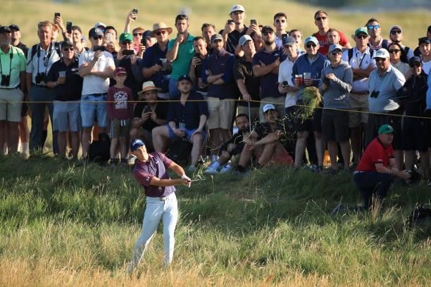 Jordan Spieth of the United States plays a shot from the rough on the 12th hole as a gallery of fans look on during Day Three of The 149th Open at...