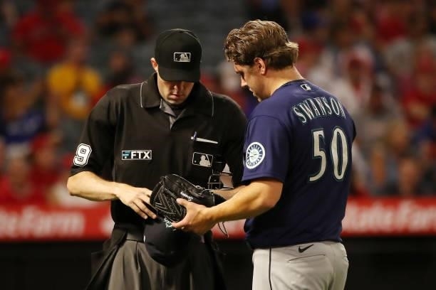 Erik Swanson of the Seattle Mariners is checked by umpire Nic Lentz at the end of the sixth inning against the Los Angeles Angels at Angel Stadium of...