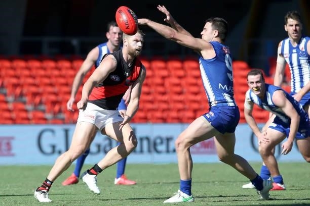 Jake Stringer of the Bombers handballs during the round 18 AFL match between North Melbourne Kangaroos and Essendon Bombers at Metricon Stadium on...