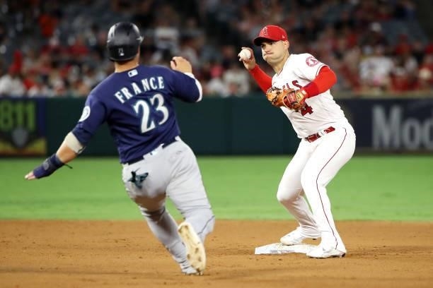 Jose Iglesias of the Los Angeles Angels throws the ball to first base while Ty France of the Seattle Mariners slides into second base during the...