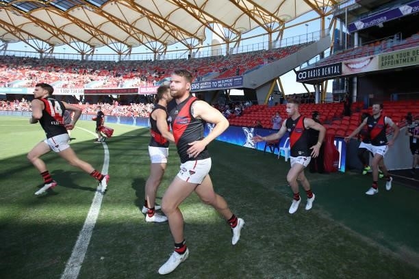 The Bombers run out during the round 18 AFL match between North Melbourne Kangaroos and Essendon Bombers at Metricon Stadium on July 18, 2021 in Gold...
