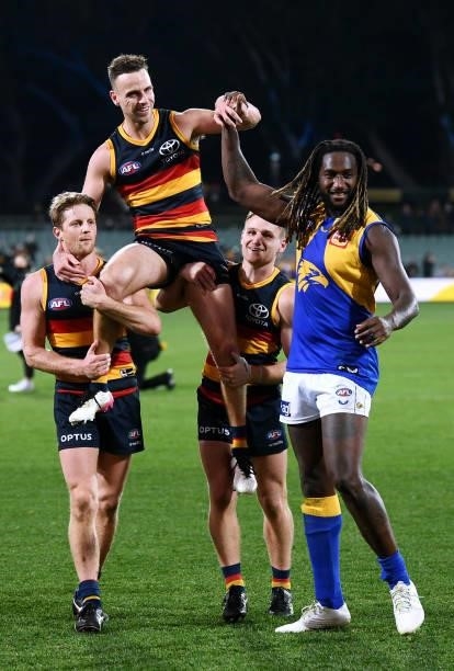 Brodie Smith of the Crows carried by Rory Sloane and Rory Laird of the Crows for his 200th game is congratulated by Nic Naitanui of the Eagles who is...