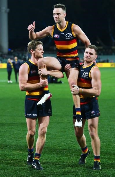 Brodie Smith of the Crows chaired off by Rory Sloane and Rory Laird of the Crows for his 200th game during the round 18 AFL match between Adelaide...