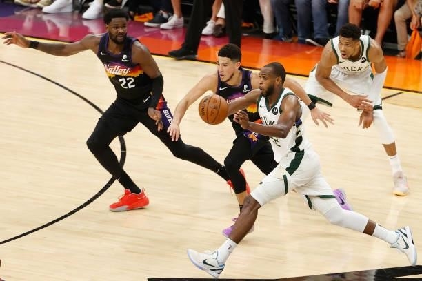 Khris Middleton of the Milwaukee Bucks passes the ball ahead of Devin Booker and Deandre Ayton of the Phoenix Suns in the second half of game five of...