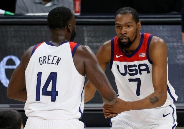 Draymond Green of the United States helps teammate Kevin Durant up from the court after he made a shot against Spain and was fouled during an...