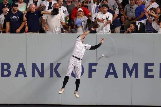 Right fielder Trey Amburgey of the New York Yankees crashes into the wall but can"u2019t make a catch on a double hit by Christian Vázquez of the...