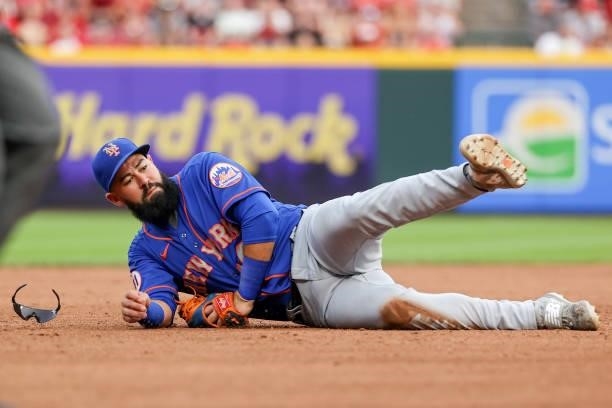 Luis Guillorme of the New York Mets falls to the ground after attempting a throw to third base in the second inning against the Cincinnati Reds at...