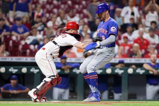 Tucker Barnhart of the Cincinnati Reds tags out Brandon Nimmo of the New York Mets at home plate in the eleventh inning at Great American Ball Park...