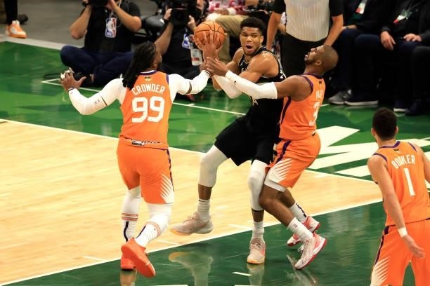 Giannis Antetokounmpo of the Milwaukee Bucks is pressured by Chris Paul and Jae Crowder of the Phoenix Suns in Game Six of the NBA Finals at Fiserv...