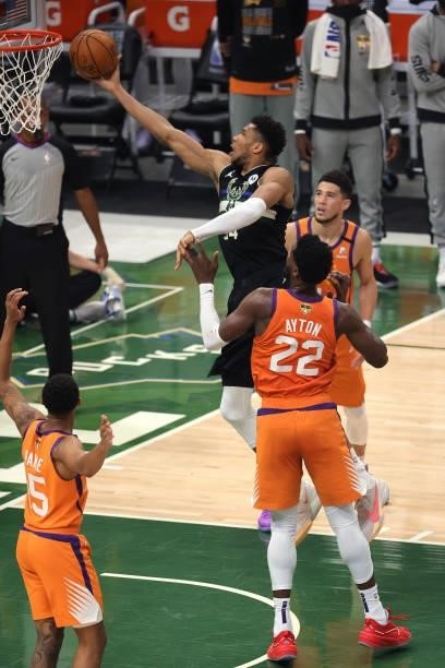 Giannis Antetokounmpo of the Milwaukee Bucks goes up for a shot against Deandre Ayton and Devin Booker of the Phoenix Suns during the first half in...