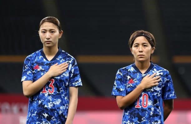 Yuzuho Shiokoshi and Mana Iwabuchi of Team Japan stand for the national anthem prior to the Women's First Round Group E match between Japan and...