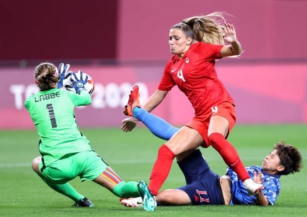 Shelina Zadorsky of Team Canada battles for possession with Mina Tanaka of Team Japan as Stephanie Labbe of Team Canada collects the ball during the...