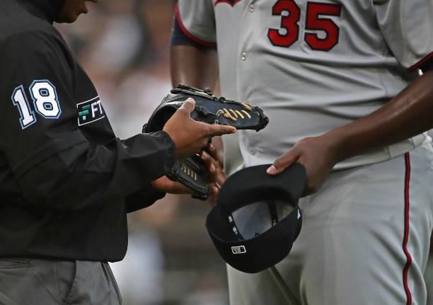 Umpire Ramon De Jesus inspects the glove and hat of starting pitcher Michael Pineda of the Minnesota Twins between inning against the Chicago White...