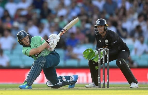 Sam Billings of Oval Invincibles hits out watched by Jos Buttler of Manchester Originals during the Hundred match between Oval Invincibles and...