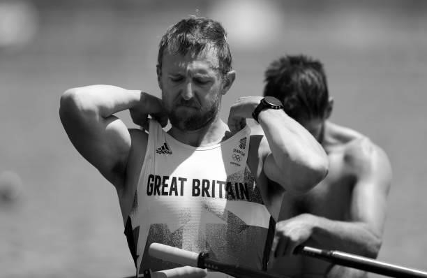 John Collins of Team Great Britain looks on at the start line and adjusts his all in one before he competes in the Men's Quadruple Sculls during the...
