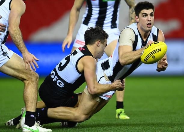 Brayden Maynard of the Magpies handballs whilst being tackled by Karl Amon of the Power during the round 19 AFL match between Port Adelaide Power and...