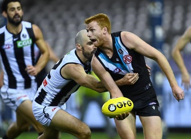 Willem Drew of the Power handballs whilst being tackled by Steele Sidebottom of the Magpies during the round 19 AFL match between Port Adelaide Power...