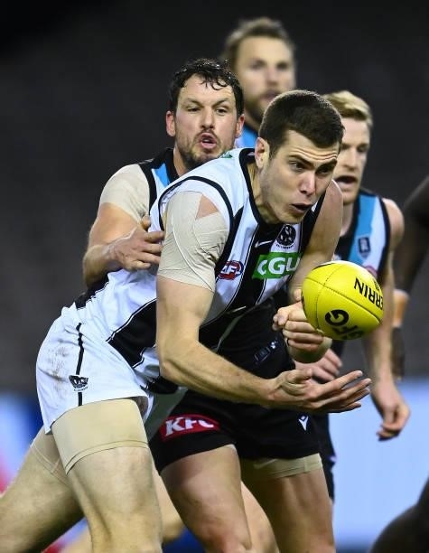 Mason Cox of the Magpies handballs whilst being tackled by Travis Boak of the Power during the round 19 AFL match between Port Adelaide Power and...