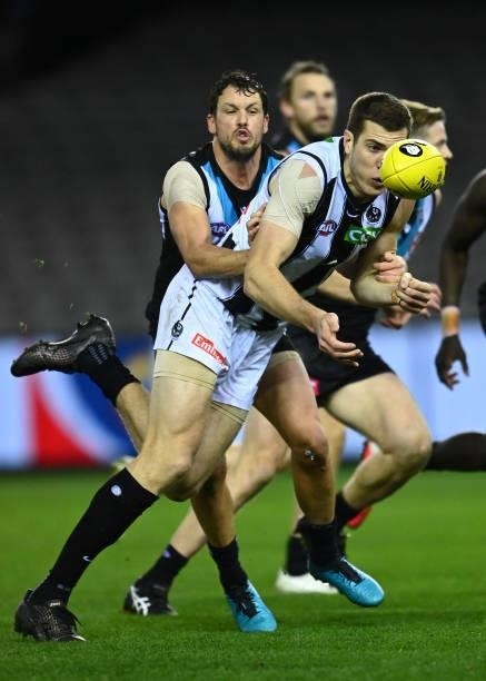 Mason Cox of the Magpies handballs whilst being tackled by Travis Boak of the Power during the round 19 AFL match between Port Adelaide Power and...