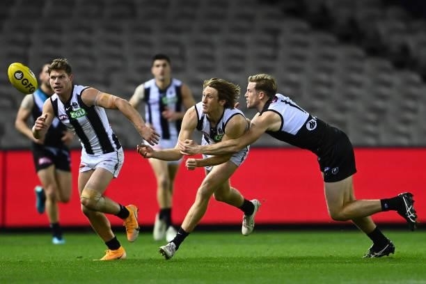Nathan Murphy of the Magpies handballs whilst being tackled by Tom Jonas of the Power during the round 19 AFL match between Port Adelaide Power and...