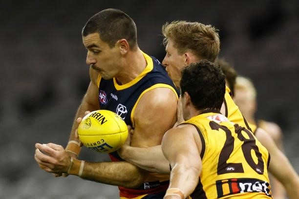 Taylor Walker of the Crows handballs whilst being tackled by Sam Frost of the Hawks during the round 20 AFL match between Adelaide Crows and Hawthorn...