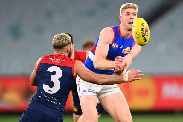 Tim English of the Bulldogs handballs whilst being tackled by Christian Salem of the Demons during the round 20 AFL match between Melbourne Demons...
