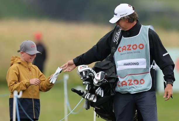 Alan Burns, caddie to Justin Harding gives a young fan a glove as they leave the first tee during the third round of the Cazoo Open supported by...
