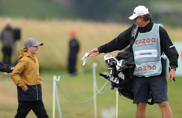 Alan Burns, caddie to Justin Harding gives a young fan a glove as they leave the first tee during the third round of the Cazoo Open supported by...