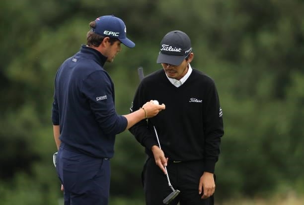 Nacho Elvira of Spain shows Masahiro Kawamura of Japan his ball which needed changing after thinning it out of the 18th greenside bunker during the...
