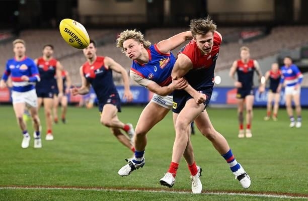 James Jordan of the Demons handballs whilst being tackled by Cody Weightman of the Bulldogs during the round 20 AFL match between Melbourne Demons...