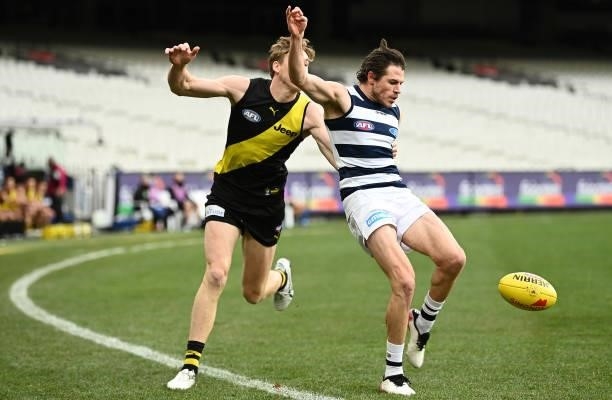 Isaac Smith of the Cats kicks whilst being tackled by Tom J. Lynch of the Tigers during the round 19 AFL match between Geelong Cats and Richmond...