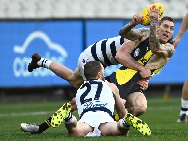 Matthew Parker of the Tigers handballs whilst being tackled by Sam Menegola and Jed Bews of the Cats during the round 19 AFL match between Geelong...
