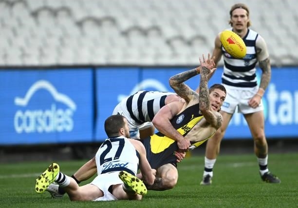 Matthew Parker of the Tigers handballs whilst being tackled by Sam Menegola and Jed Bews of the Cats during the round 19 AFL match between Geelong...