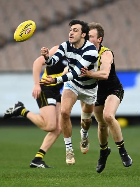 Brad Close of the Cats handballs whilst being tackled during the round 19 AFL match between Geelong Cats and Richmond Tigers at Melbourne Cricket...