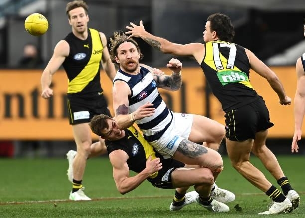 Zach Tuohy of the Cats handballs whilst being tackled by Jake Aarts of the Tigers during the round 19 AFL match between Geelong Cats and Richmond...