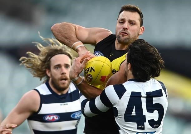 Toby Nankervis of the Tigers handballs whilst being tackled by Brad Close of the Cats during the round 19 AFL match between Geelong Cats and Richmond...