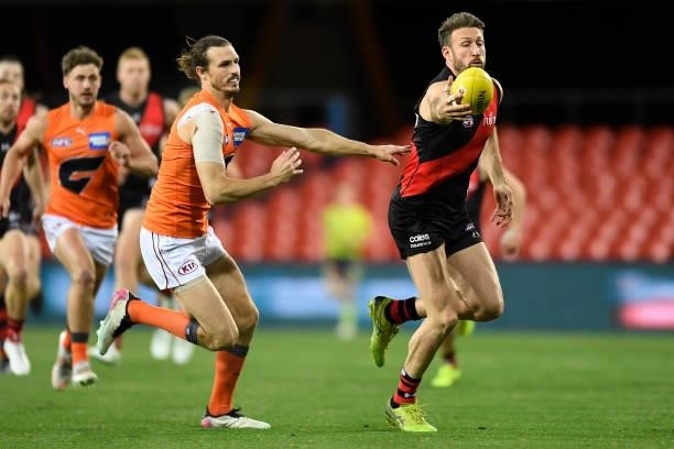 Cale Hooker of the Bombers controls the ball in front of Phil Davis of the Giants during the round 19 AFL match between Essendon Bombers and Greater...