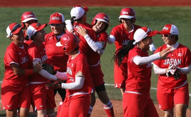 Eri Yamada of Team Japan celebrates her game-winning RBI in the eighth inning against Team Canada with teammates during the Softball Opening Round on...