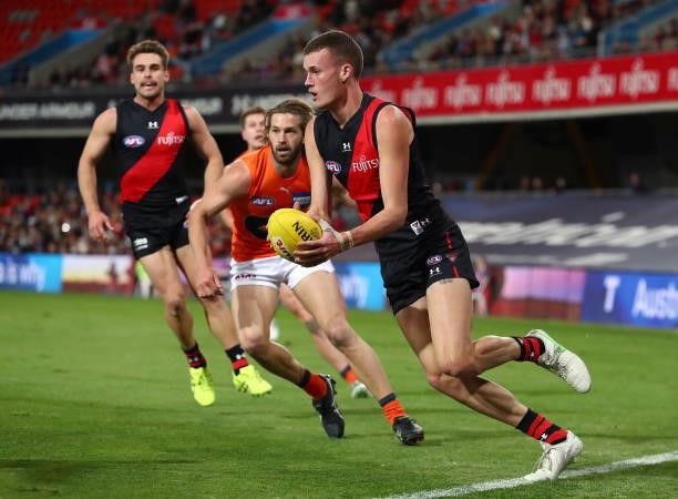 Nik Cox of Essendon runs with the ball during the round 19 AFL match between Essendon Bombers and Greater Western Sydney Giants at Metricon Stadium...