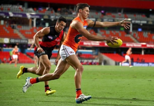 Isaac Cumming of the GWS Giants kicks the ball under pressure from Dylan Shiel of Essendon during the round 19 AFL match between Essendon Bombers and...