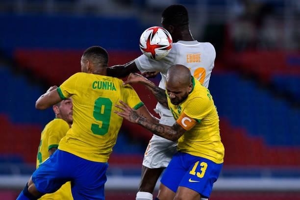 Matheus Cunha of Brazil, Eboue Kouassi of Ivory Coast and Dani Alves of Brazil compete for the headed ball during the Tokyo 2020 Olympic Mens...