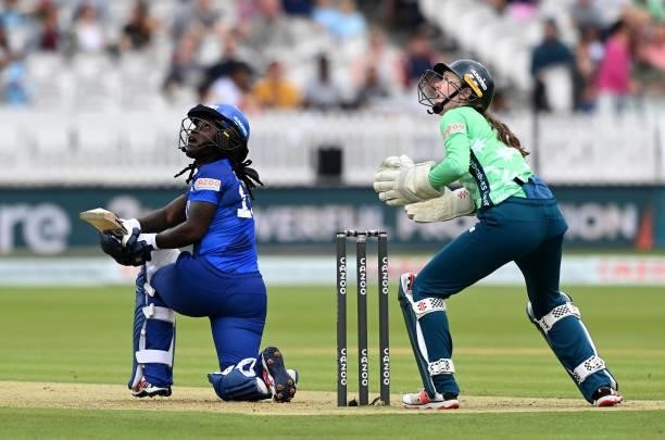 Deandra Dottin of London Spirit Women plays a shot as Oval Invincibles wicket keeper Sarah Bryce looks on during The Hundred match between London...