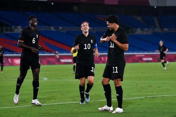 Ragnar Ache of Germany and Max Kruse of Germany walk to Nadiem Amiri of Germany who celebrates after scoring his sides first goal during the Tokyo...